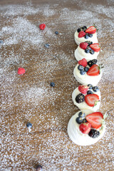 A festive Pavlova dessert made of meringue, whipped cream, and fresh berries. Ideal for celebrations, birthdays, or Christmas. Photographed on a rustic background with powdered sugar.”
