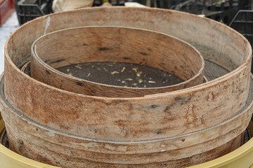 Multiple wooden sieves are stacked on top of each other at a harvest site, revealing signs of use.
