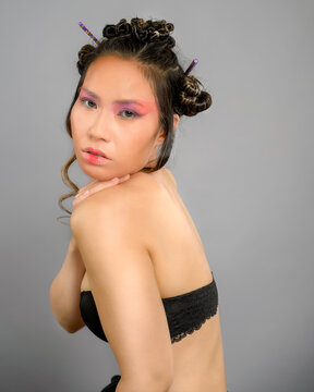 Creative Asian Beauty Portrait of Woman with Artistic Makeup and Hair Buns