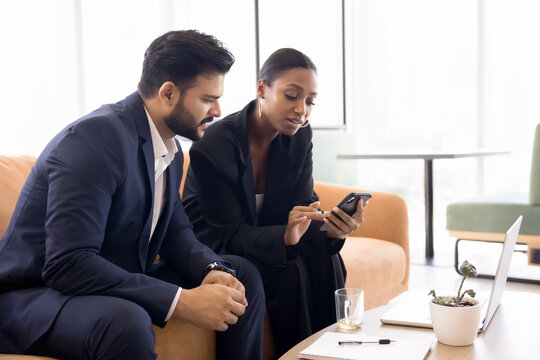 Consulting service and technology. Smart female realtor insurer show digital document presentation to young businessman client on cellphone screen make tax loan rate calculations using app. Copy space