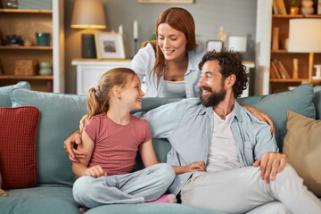 Obraz premium A family of three shares joyful moments on a comfortable couch in their inviting living room, creating treasured memories with laughter and love during their time together.