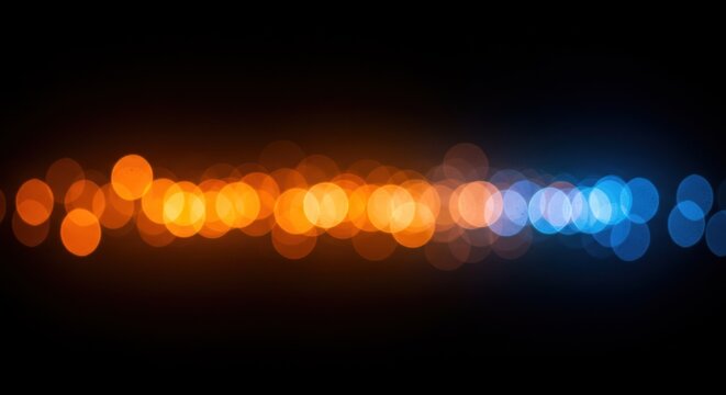 Abstract bokeh lights in orange and blue colors on a dark background.