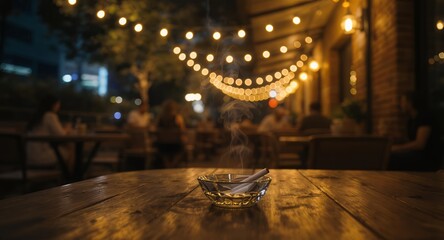 Smoking cigarette in an ashtray on a wooden table at night