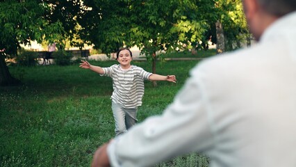 Little daughter runs to her father in park hugs him. Concept happy family. Child girl meets her dad in summer park. Girl family walk with her grandfather outdoors in summer. Family people together
