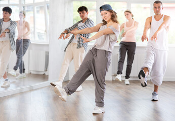 Dynamic young woman training hip hop kick steps in dancehall during workout session