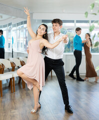 Enthusiastic young couple, elegant Latin American guy and dark-haired girl in formal wear,...