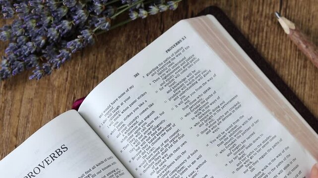 Hand is turning pages of open holy bible book. Christian morning study, biblical concept.