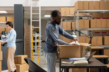 Black male employee reviewing shipment logistics for distribution hub, working in the shipping area...
