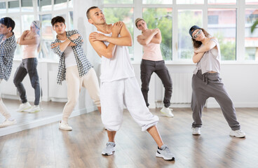 During hip hop dance lesson, guy leads, conducts classes, teaches students to correctly perform...