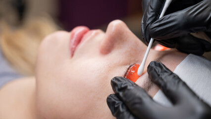 Caucasian woman undergoing eyelash lamination procedure. 