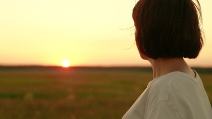 Girl dreamily looks at sunset sky, hair fluttering in wind. Young thoughtful woman outdoors, sunrise, travel. Portrait face of beautiful woman close-up, nature. Nature people vacation travel lifestyle