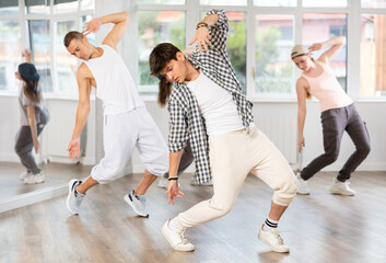 Active young guy practicing break dance in training hall during dancing classes