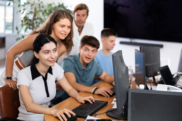 Friendly young students, girls and guys, actively involved in collaborative learning, sitting...