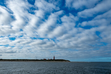 Obraz premium Eierland, De Cocksdorp, Texel, The Netherlands, Oktober 28th, 2024, A coastal scene with a charming lighthouse beneath a vast sky filled with dramatic clouds, inspiring awe