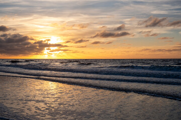 A breathtaking sunset is painting the sky with vivid and radiant colors above the gentle ocean...