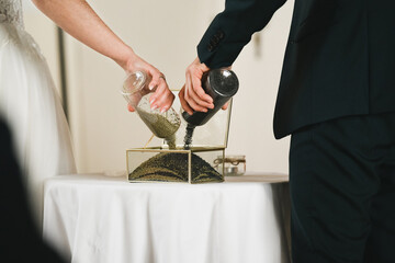 Sand ceremony at a wedding. Newlyweds mix sand into a vase