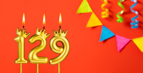 Number 129 candle - Birthday celebration on an orange background with pennants