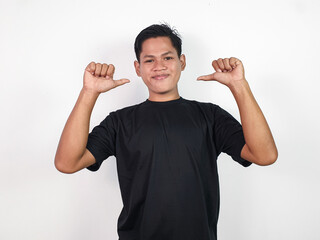 A young Asian man in black shirt confidently raises his arm and points a thumb at himself, standing...