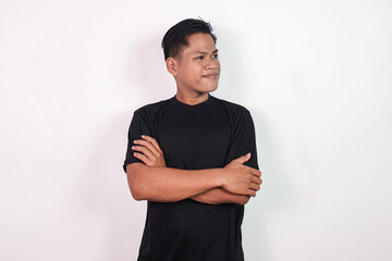 A confident Asian man stands against a plain white background, crossing his arms confidently. Ideal...