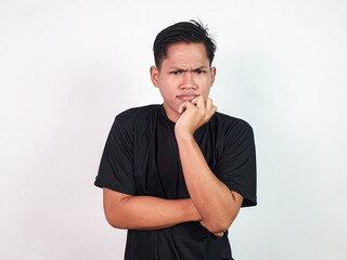 A young Asian man wearing a black shirt is posing thoughtfully, with one hand on his chin and a...