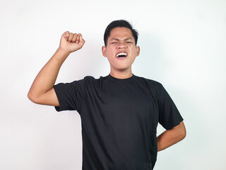 A young Asian man in a black shirt enthusiastically gestures, signifying joy, success, or victory....
