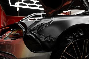 Matte black vinyl wrap application on front fender and wheel arch of luxury vehicle. Vinyl Wrapping...