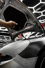 Vinyl film is carefully applied and trimmed with a blade for flawless vehicle wrapping results. Wrapping vinyl requires perfect tension and accurate blade work for high-end detailing.