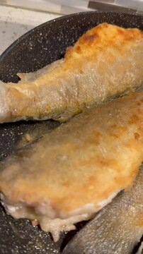 Turkish sea bass (levrek) frying in a pan. Fresh Mediterranean fish sizzling in oil, a traditional cooking scene. Food and culinary