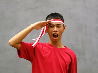 Indonesian boy wearing a red and white headband with salutes pose, celebrating Indonesian...