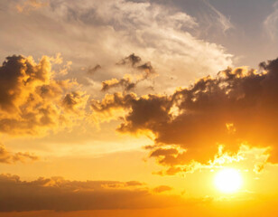 Obraz premium Breathtaking sunset showcases dramatic sky filled with vibrant orange and yellow hues, complemented by fluffy clouds. golden hour creates warm, serene atmosphere, perfect for reflection