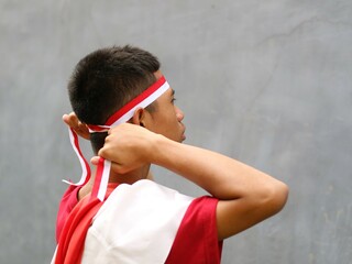 Indonesia boy in red shirt holding ribbon on his head, Indonesia independence day celebration...