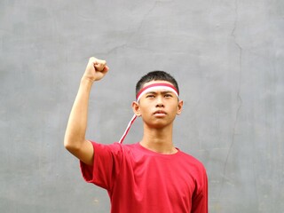 Indonesian boy in red shirt  with red white headband, his fist raised upwards, during Indonesia's...
