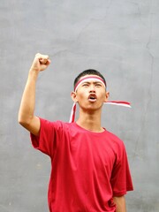 Indonesian boy in red shirt  with red white headband, his fist raised upwards, during Indonesia's...