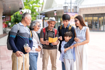 Family multigenerational travelers reading tourist guide and map planning travel with grandparents parents and child, smiling group enjoying vacation moment, big family trip, lifestyle and tourism