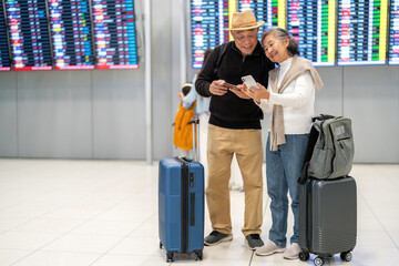 Senior asian couple sitting with luggage checking passport planning trip showing travel preparation at airport, retirement lifestyle enjoying international travel, safe travel, elderly trip insurance