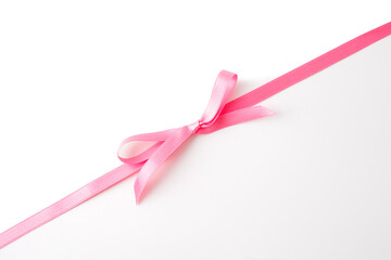 decorative pink bow with satin texture slightly off center on white background top view ribbon accessory for gift wrap charity campaign greeting card design packaging branding layout product photo