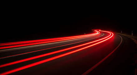 Long exposure of car lights on a winding road at night time creates a dynamic abstract pattern