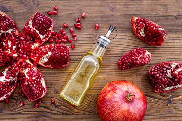 Glass bottle of pomegranate seed oil in a glass bottle and fresh fruit on a table, top view