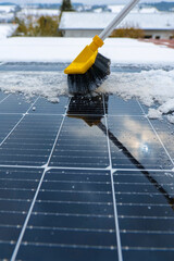  Cleaning solar panels from snow.Yellow brush clears snow from solar panel close-up.