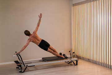 A man doing Pilates on a reformer. 