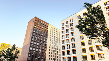 Modern residential high-rise buildings in bright sunlight against clear blue sky, concept of real estate purchase and rent