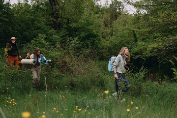 Obraz premium Middle aged woman hiking outdoors with two companions in lush green forest, enjoying active and healthy lifestyle focused on fitness and wellbeing in nature.