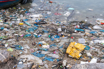 Pollution crisis at riverside exposed as debris accumulates along the shoreline during a cloudy afternoon