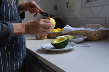 Woman's hands preparing avocado with lemon and salt in the kitchen.