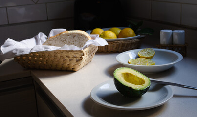 Half an avocado, lemons, salt, and homemade bread on the kitchen counter.