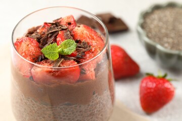 Delicious chocolate pudding with chia seeds, strawberries and mint on table, closeup. Space for text