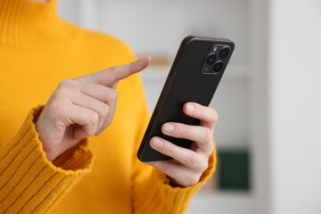 Woman using modern smartphone at home, closeup