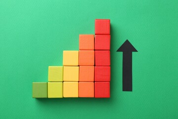 Maximum. Arrow and colorful cubes on green background, top view
