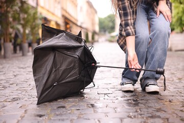 Woman taking broken umbrella on wet pavement outdoors, closeup