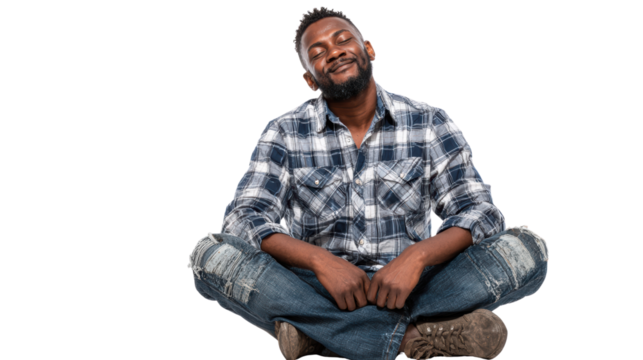Smiling man sitting cross-legged in casual attire, expressing joy and relaxation.